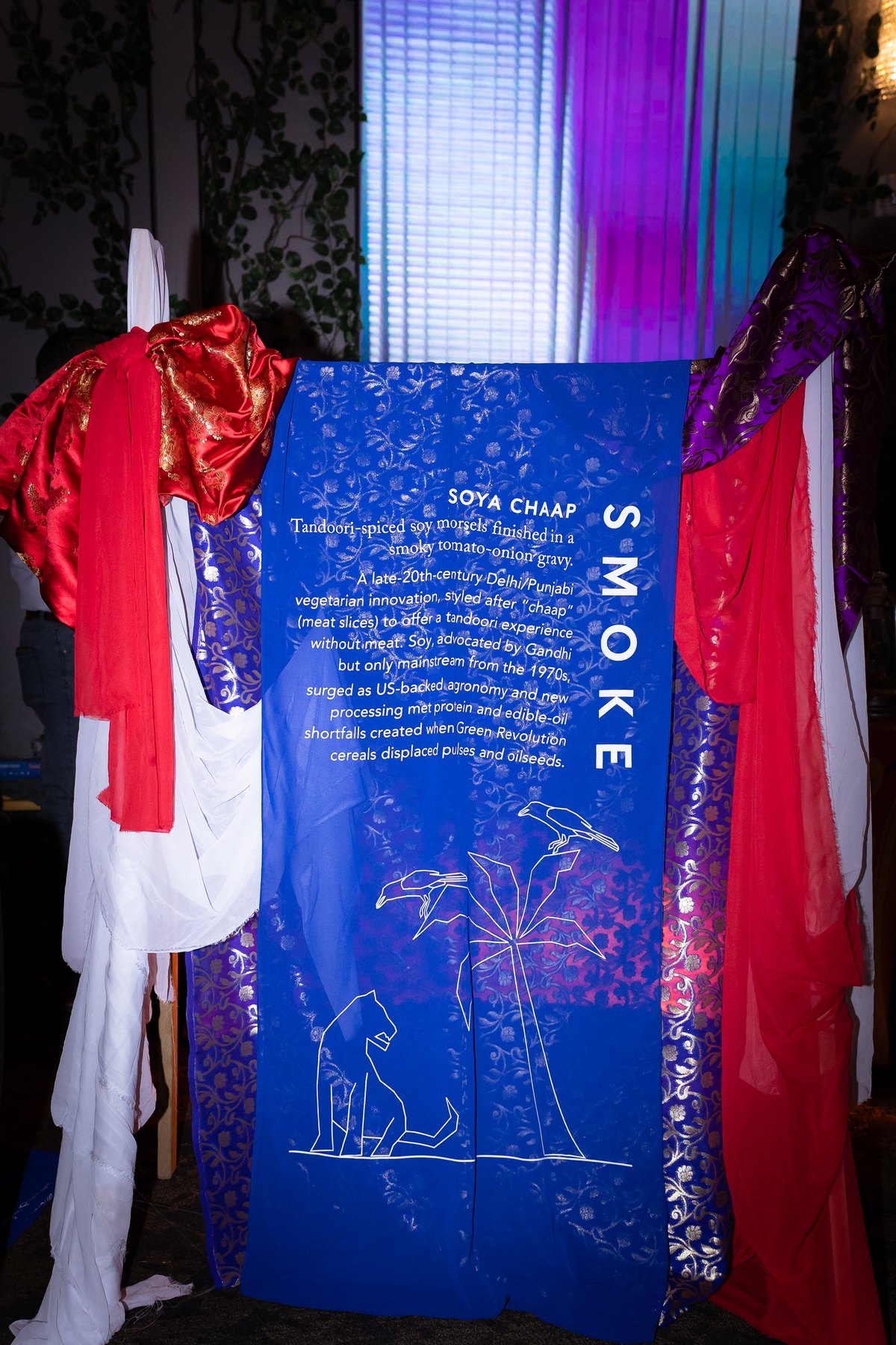 Blue soya chaap wedding menu sign surrounded by red and purple fabric.